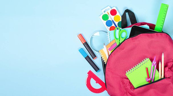 backpack with school supplies on a light blue background - Фото, изображение