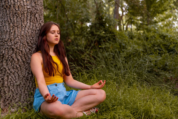 Young caucasian girl meditating in the park - Foto, afbeelding