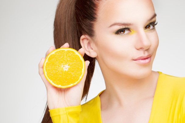 Young brunette with orange in her hand - Photo, Image