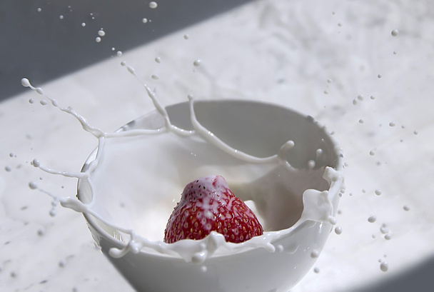 Fresa salpica en taza de leche
 - Foto, imagen