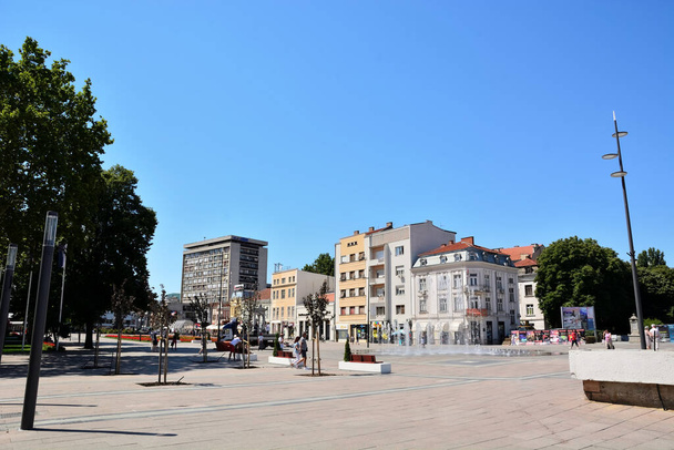 Nis, Serbia - 08 de agosto de 2021 Gran paseo marítimo y plaza con fuente y edificio antiguo en un día soleado de verano. Pueblos caminando y disfrutando en el día - Foto, imagen