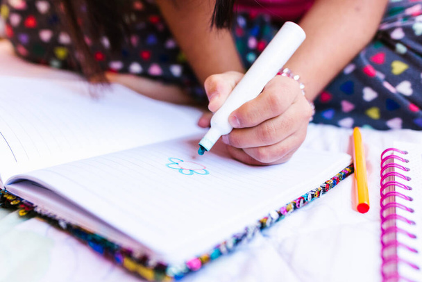 Latin girl with down syndrome drawing in notebook, in disability concept in Latin America - 写真・画像