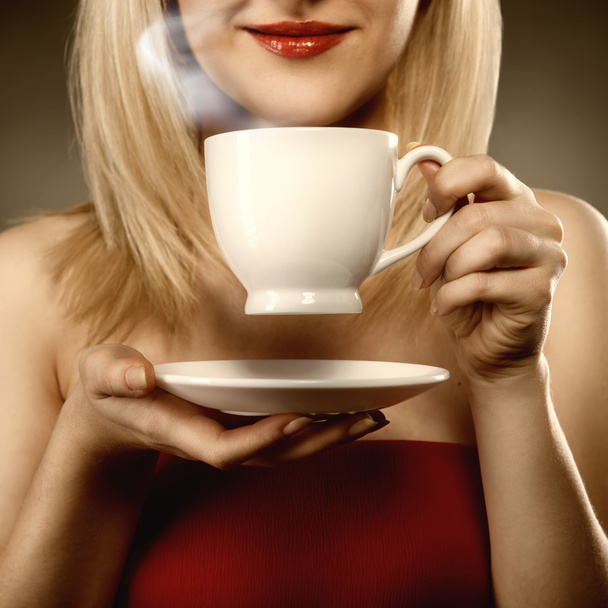 woman in red holding cup and smiles - Foto, Imagem