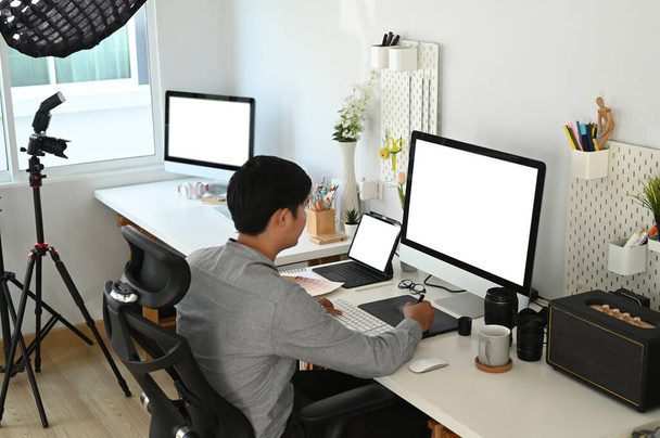 Designer gráfico ou fotógrafo está trabalhando com computador de tela vazia e tablet digital em seu espaço de trabalho. - Foto, Imagem