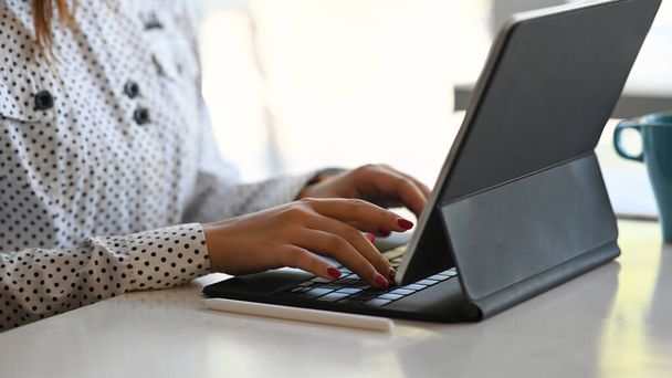 Обрізаний знімок жінки за допомогою комп'ютерного планшета, який шукає інформацію в Інтернеті на своєму робочому місці
. - Фото, зображення