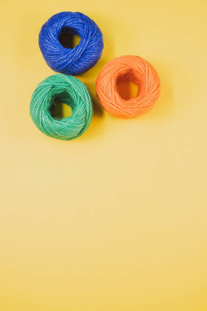 A closeup shot of soft colorful textile balls of wool on a yellowbackground with a copy space - Foto, Bild