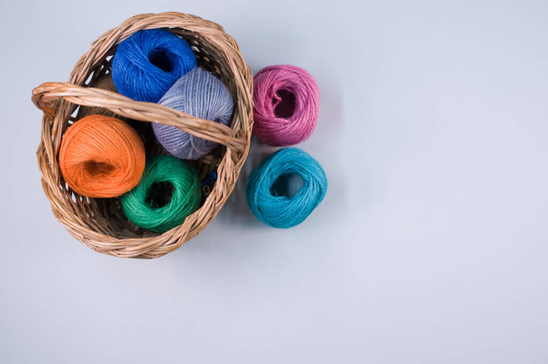 A pile of colorful textile balls of wool in a wicker basket on blue background with a copy space - Foto, Bild