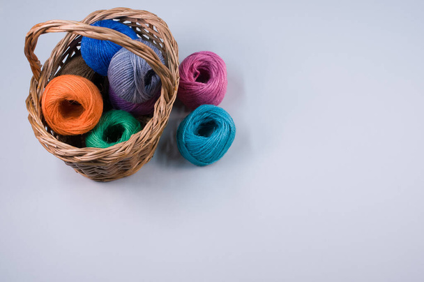 Hromada barevných textilních kuliček vlny v proutěném koši na modrém pozadí s kopírovacím prostorem - Fotografie, Obrázek