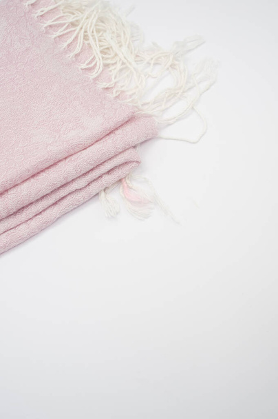 A closeup shot of a folded pale pink scarf with white tassels with a copy space - Foto, imagen