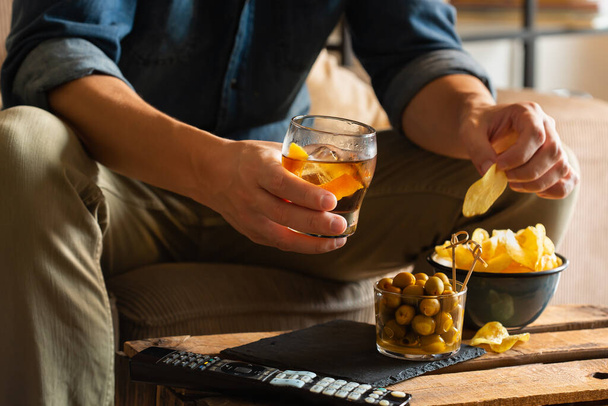 Uomo che beve vermouth e mangia snack dopo il lavoro a casa - Foto, immagini