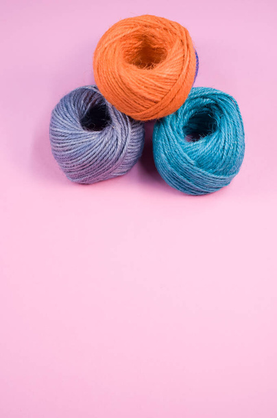 A closeup shot of soft colorful textile balls of wool on a pink background with a copy space - Foto, imagen