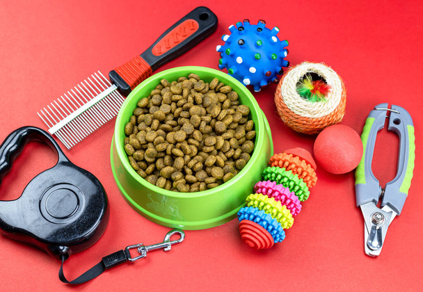 Tierfutter in Schalen, Spielzeug, für Haustiere auf rotem Hintergrund - Foto, Bild