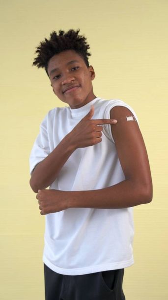 Афро-американский подросток весело показывает повязку на вакцине COVID-19 - Фото, изображение