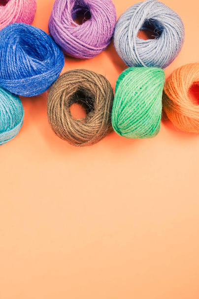A closeup shot of soft colorful textile balls of wool on orange background with a copy space - Foto, afbeelding