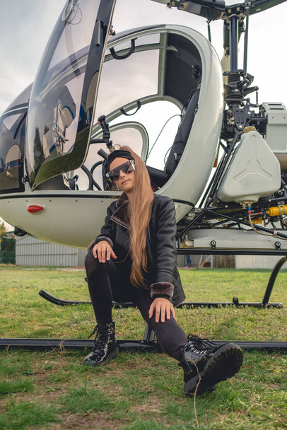 Між дівчиною сидить на підніжжі відкритого вертольота
 - Фото, зображення