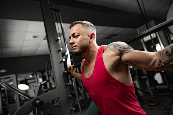Portrait of man bodybuilder in red shirt in gym - Foto, immagini