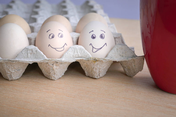 Two eggs painted with smiling face next to a red coffee cup. Good morning breakfast concept. - 写真・画像