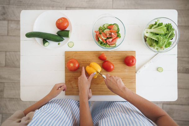 Close up of a woman and girl cutting vegetables for salad in kitchen - Foto, Imagen