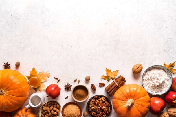 Autumn fall baking food background with pumpkins, apples, nuts and seasonal spices on white. Cooking pumpkin or apple pie and cookies for Thanksgiving and autumn holidays. - Фото, изображение