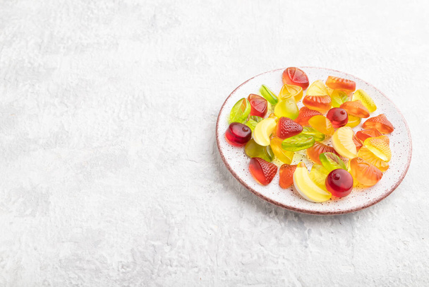 Various fruit jelly candies on plate on gray concrete background. side view, copy space. - Foto, imagen