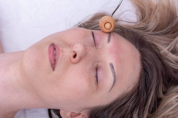 Massage the girls face with a wooden roller massager. Lymphatic drainage face massage with wooden massager - 写真・画像
