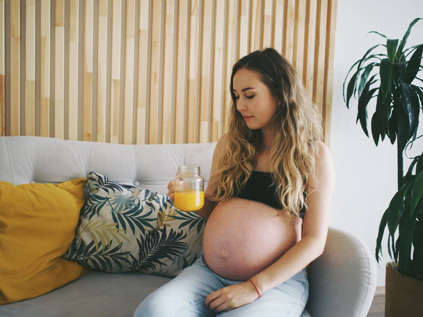 terhes nő iszik frissen facsart narancslé, vitaminok terhes nők - Fotó, kép