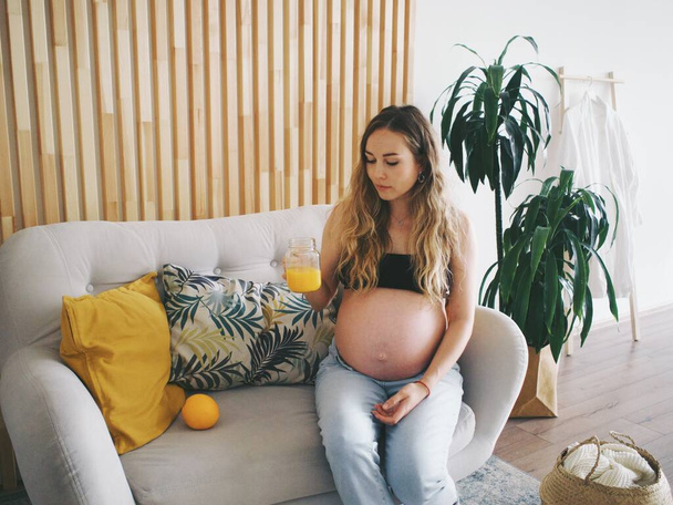 těhotná žena pije čerstvě vymačkaný pomerančový džus, vitamíny pro těhotné ženy - Fotografie, Obrázek