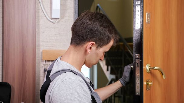 Craftsman checks entrance door lock twisting lever in room - Photo, Image