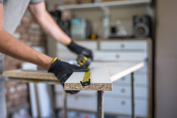 Ruce řemeslníka pomocí měřicí pásky a tužky, aby značky na kus dřeva umístěn. - Fotografie, Obrázek