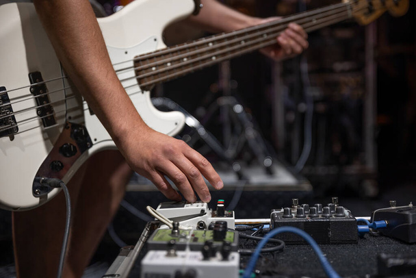 Un guitarrista masculino instalando efectos de procesamiento de audio de guitarra en el escenario. - Foto, Imagen
