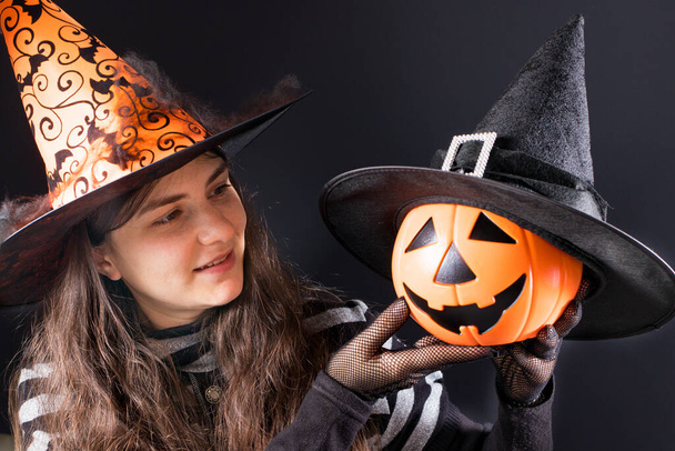 Une femme en costume de sorcière avec un chapeau orange tient une lanterne à citrouille. Halloween des gens. - Photo, image