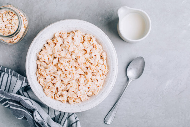Farina d'avena. sana colazione cereali ciotola con farina d'avena su sfondo grigio pietra, spazio copia, vista dall'alto. - Foto, immagini