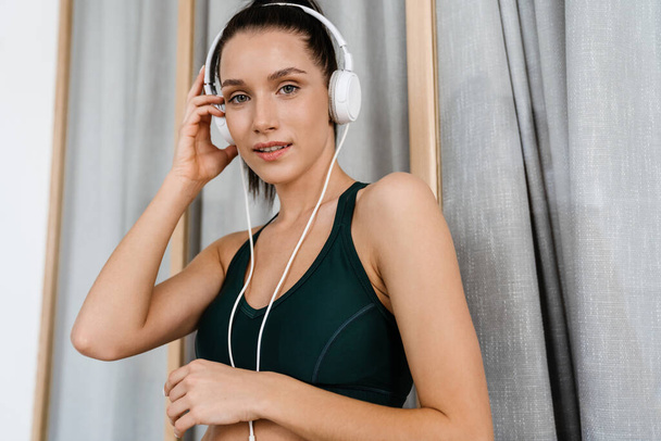 White brunette woman smiling and listening music with headphones at home - Foto, Imagem