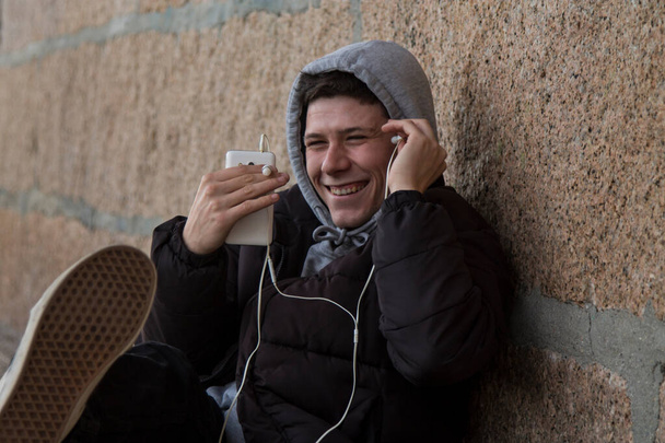 young man sitting using mobile phone with headphones - Fotó, kép
