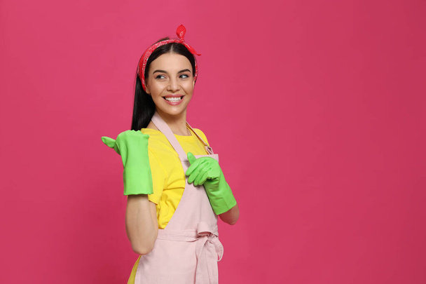 Young housewife wearing rubber gloves on pink background, space for text - Foto, Bild