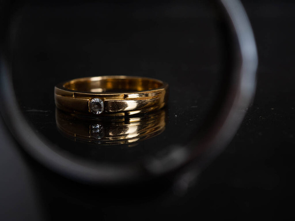 Primer plano brote de anillo de bodas de oro con hermoso diamante sobre un fondo negro - Foto, imagen