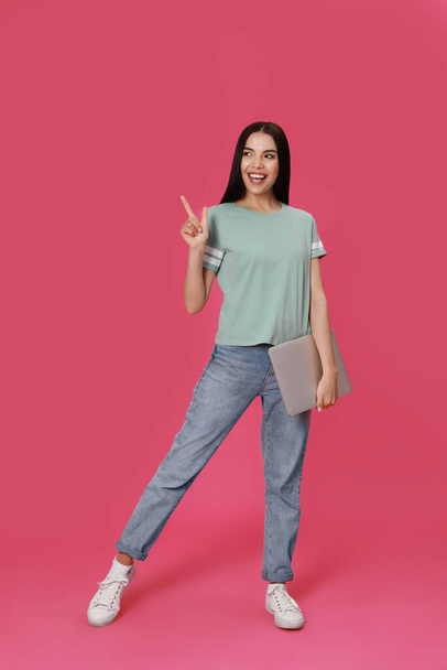 Young woman with modern laptop on pink background - Foto, afbeelding