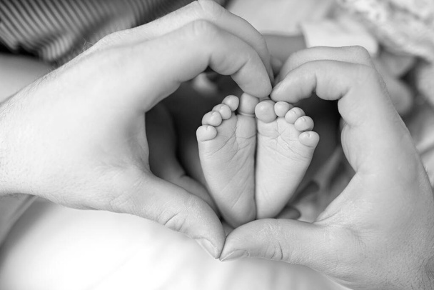Füße des Neugeborenen in den Händen der Mutter aus nächster Nähe. - Foto, Bild