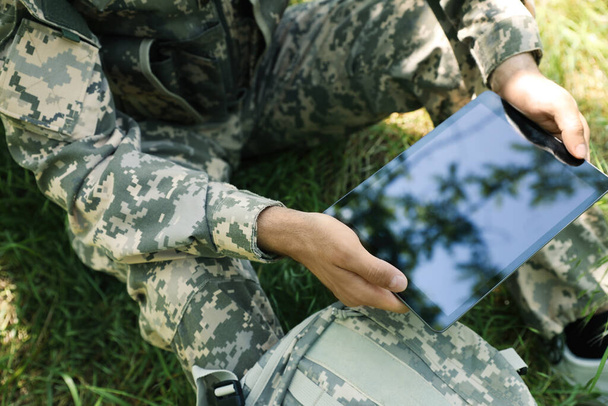 Soldier with backpack using tablet near tree in forest, closeup - Foto, immagini