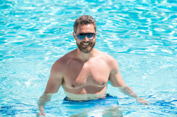 šťastný svalnatý muž v brýlích plavání v bazénu v létě, léto - Fotografie, Obrázek