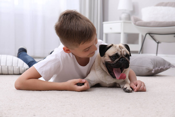 Boy with his cute pug on floor at home - Foto, imagen