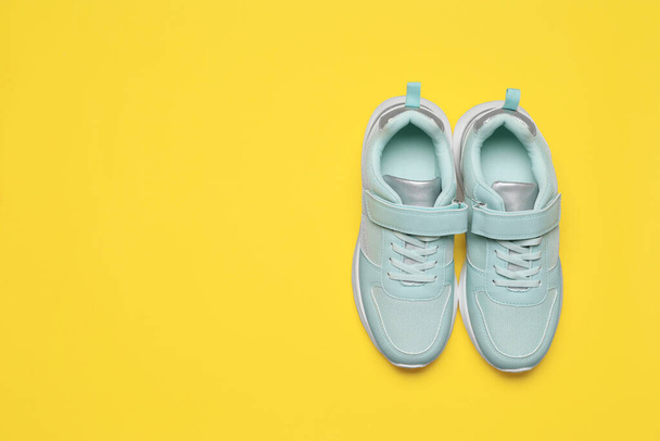 Pair of comfortable sports shoes on yellow background, flat lay. Space for text - Φωτογραφία, εικόνα