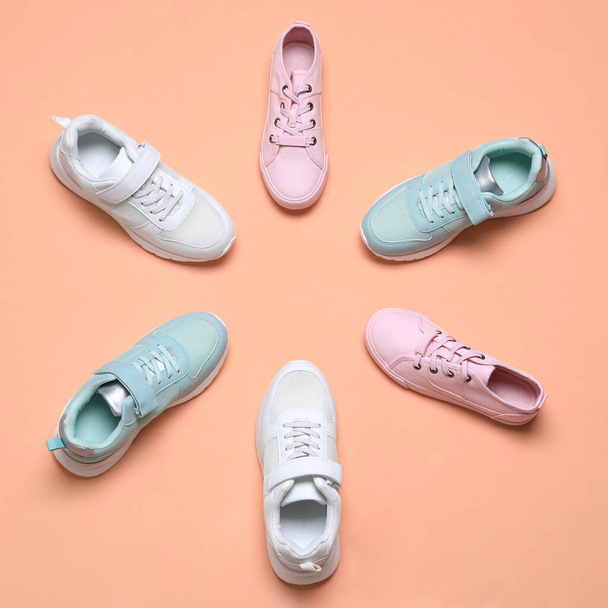 Flat lay composition with different stylish sports shoes on pale coral background - Photo, Image
