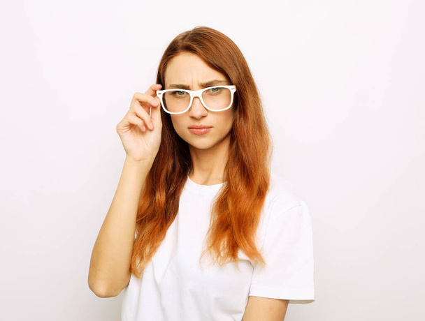 Portrait of trendy, caucasian, cheerful, modern, nice, stylish, cute, ginger woman in eyewear isolated on grey background, looking at camera - Foto, afbeelding