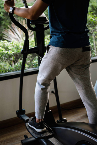 トレーニングジムのコンセプト彼の健康的なルーチンとしてジムでサイクリングマシンで心臓トレーニングを行う男性ティーネージャー. - 写真・画像