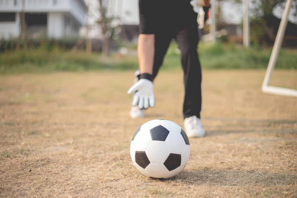 Koncepcja sportu i rekreacji męski bramkarz stojący przed bramką rzucając piłkę jako dystrybucję do gracza po ochronie celu. - Zdjęcie, obraz