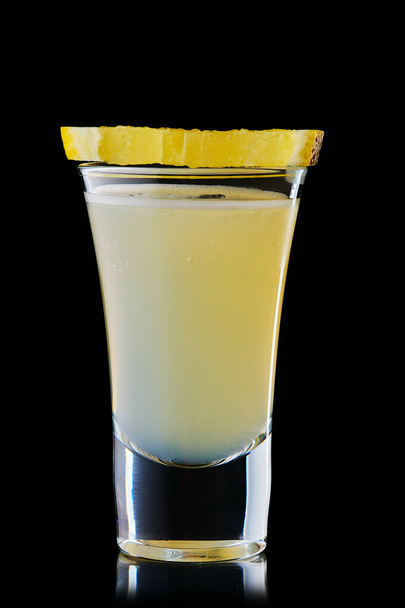 Shot with vodka and lemon juice isolated on black background - Foto, afbeelding
