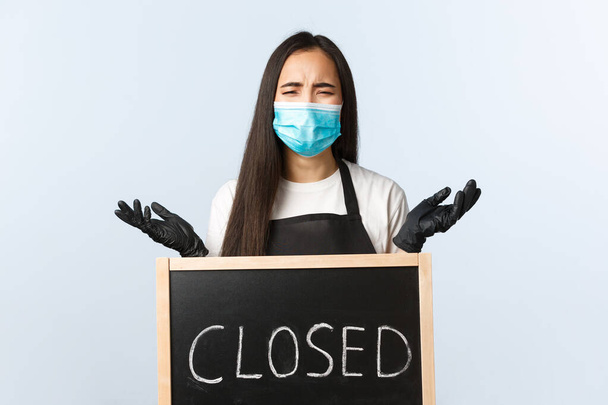 Small business, covid-19 pandemic, preventing virus and employees concept. Upset desperate cafe owner left without work and business during lockdown, crying over closed sign - Foto, Imagem