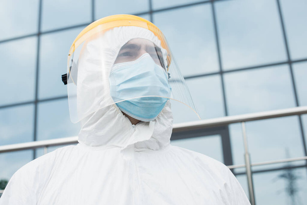 Low angle view of medical worker in hazmat suit and safety visor outdoors  - Fotoğraf, Görsel