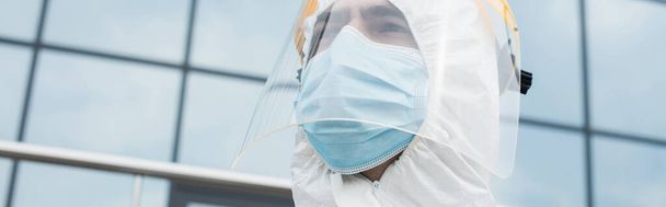 Low angle view of medical worker in visor and protective mask outdoors, banner  - Fotoğraf, Görsel